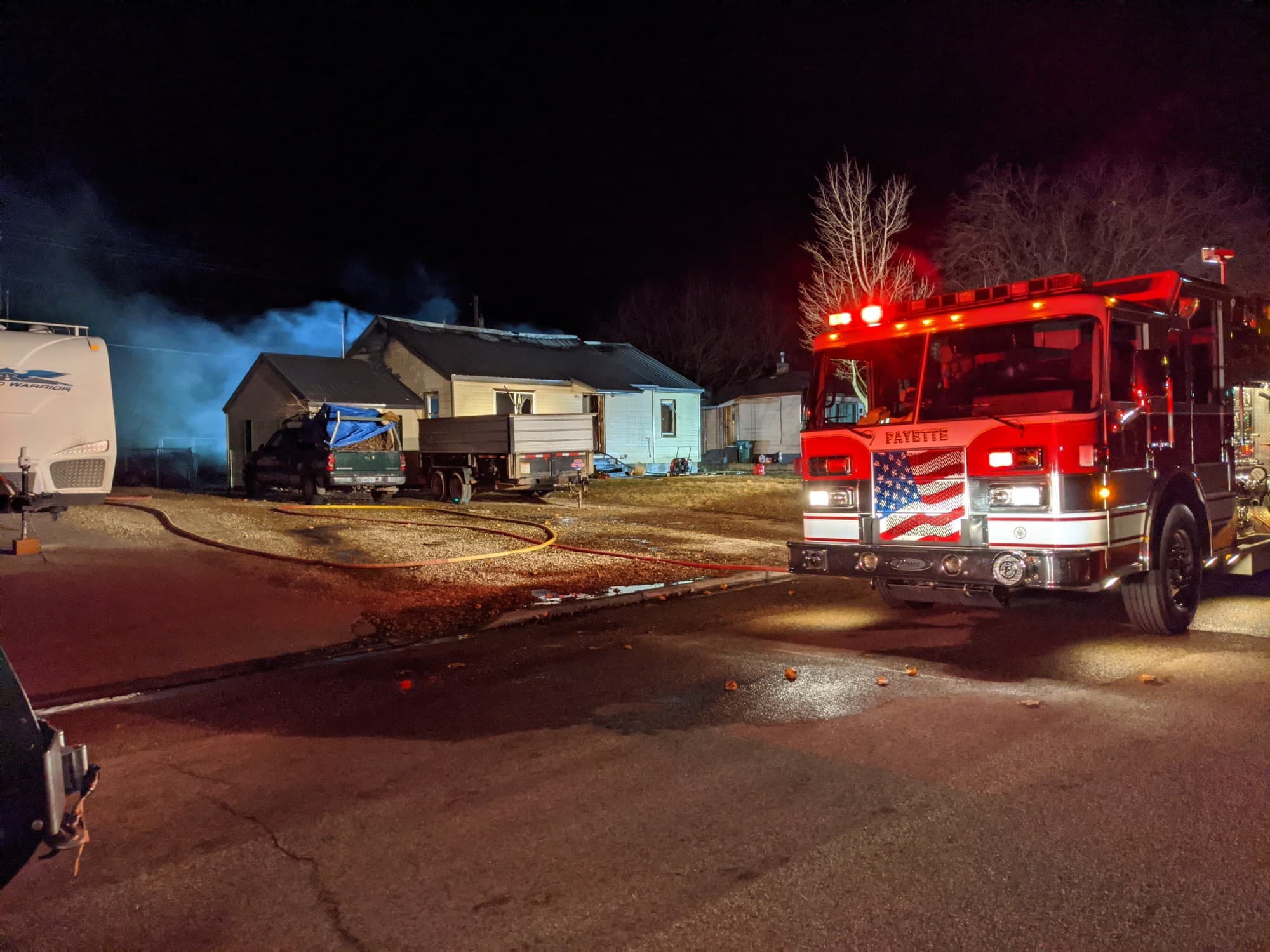 A Payette fire engine on scene at night, red lights turning and the flag flying